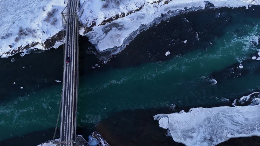 Aerial top down of cars on Bridge over Selfoss River with ice floe in winter. Snowy winter landscape in Iceland.