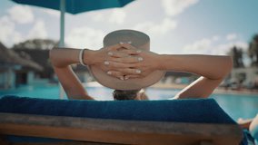 Female vacationer relaxing near swimming pool, woman lying on lounger, rearview . Be happy and calm, recovery vitality and soul health by traveling, spending summer holidays in tropical countries - Powered by Shutterstock - Get 15% off with code: PIKWIZARD15