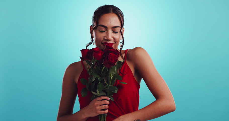 Smell, flowers and face of woman in studio with smile, happy celebration or valentines day gift. Red roses, romantic offer and female person with bouquet, floral present or love on blue background