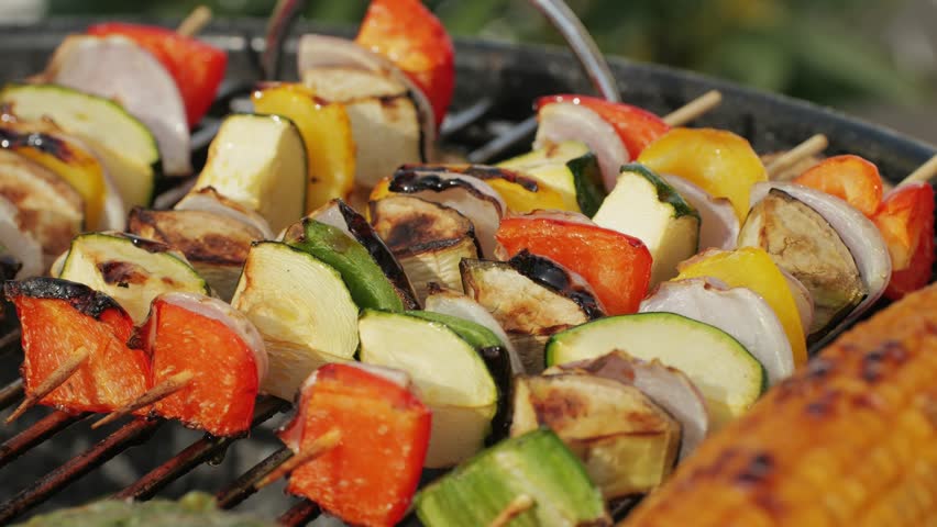 Cooking many various of vegetables on grill close-up. Making vegan, vegetarian kebab and veggie cutlets for burgers. Fry corn, red pepper, zucchini and onion. Barbecue for friends and family. Cafe and