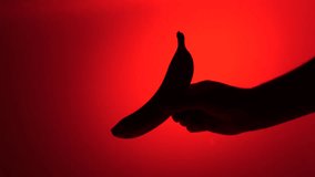 Hand holding banana silhouette on red background - Powered by Shutterstock - Get 15% off with code: PIKWIZARD15
