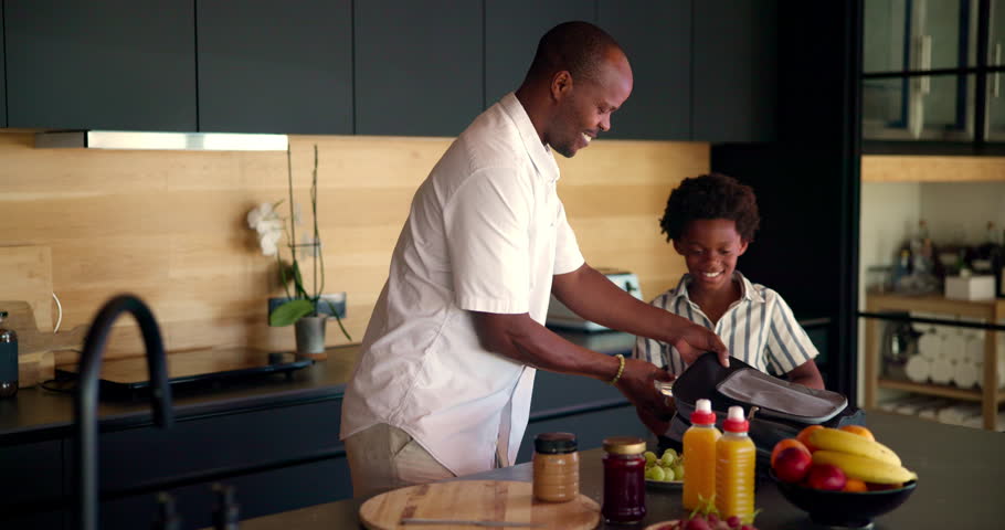 Child, father and packing school lunch in home for morning routine, healthy nutrition or education support. Black family, boy and man with sandwich in backpack for lunchbox preparation or food snacks