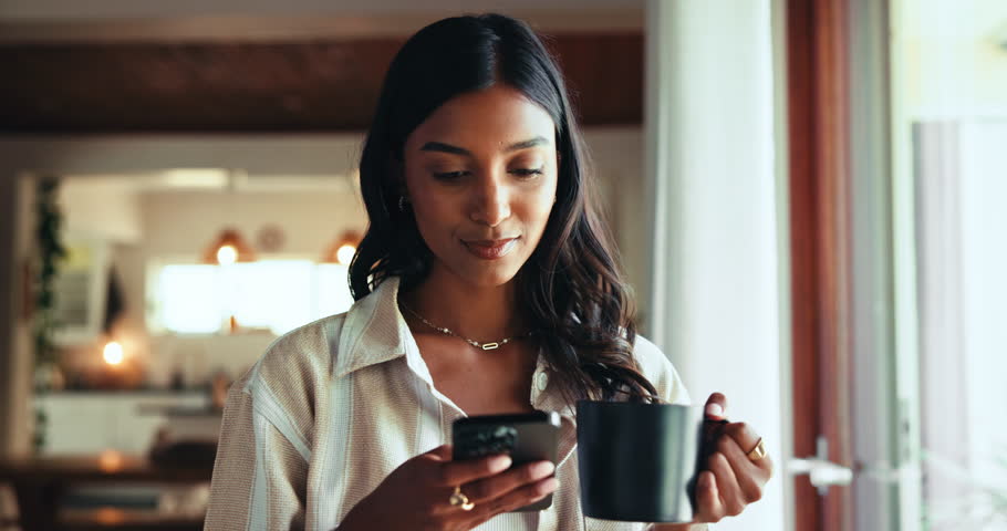 Morning, coffee and woman with smartphone, home and browsing on web for entertainment, online and relax. Living room, thinking and drinking of tea in house, digital and Indian person with mobile