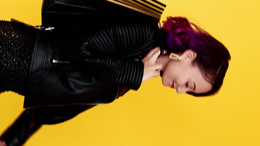 Vertical video. Black Friday shopping. Advertising consumer. Satisfied happy woman walking by with purchase mockup paper bags isolated on yellow loop.