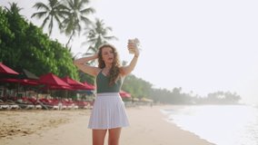 Attractive young female selfie on tropical beach during golden hour. Poses, smartphone in hand, sun tanned amidst seaside ambiance. Social media influence vivid, trendsetting digital presence. - Powered by Shutterstock - Get 15% off with code: PIKWIZARD15