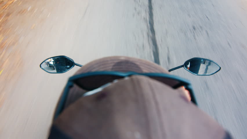 Indonesian man steers motorbike on the narrow street in Bali. POV of the driver on bike in Indonesia