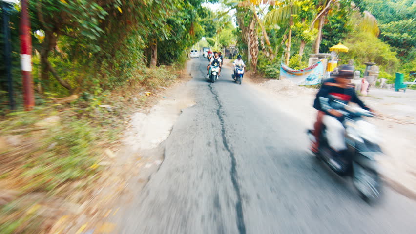 Indonesian man steers motorbike on the narrow street in Bali. POV of the driver on bike in Indonesia