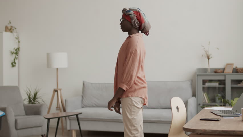 Lockdown of young African woman standing in living room, greeting African-American handyman wearing uniform and explaining him what he needs to fix