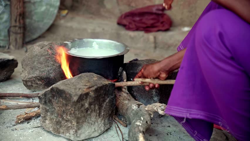 African woman setting a fire to cook milk
