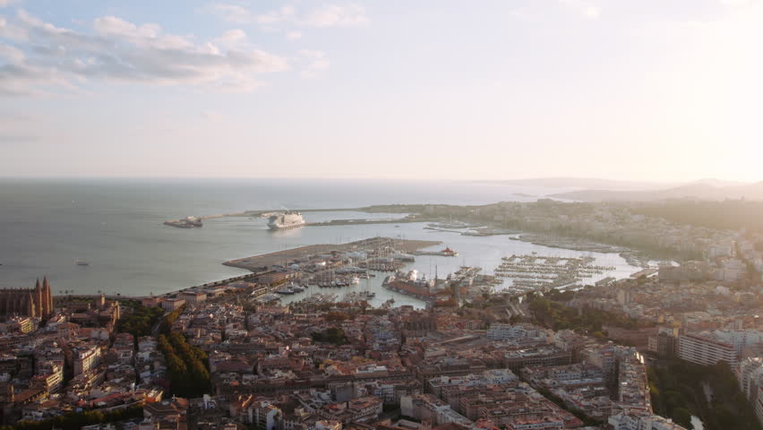 Beautiful drone shot of Palma de Mallorca city centre and harbour. Cruise ship docked at port. The Cathedral of Santa Maria of Palma, more commonly referred to as La Seu in sunset light