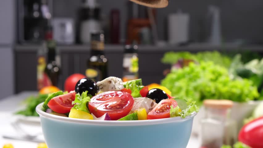 Salad sprinkled with ground pepper and spices, bowl of fresh Greek salad close-up