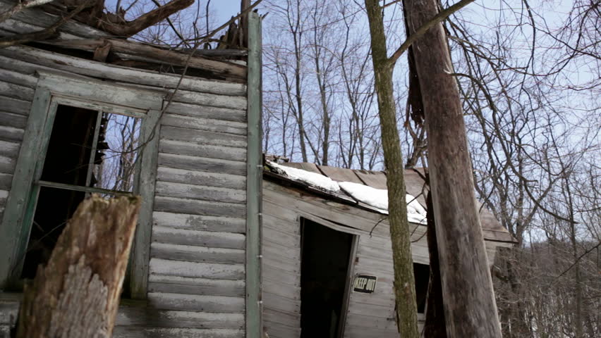 Abandoned 1910 homestead in a snowy forest in rural Wisconsin. The house is so weathered that the outer walls have collapsed and the roof lies next to it. Midwestern USA.