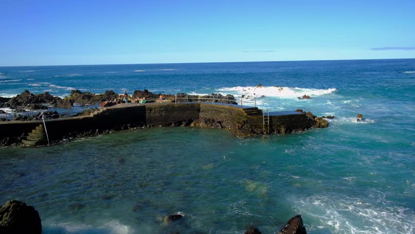 Group of People Relaxing and Enjoying the Sunny Coastline on a Clear Blue Day