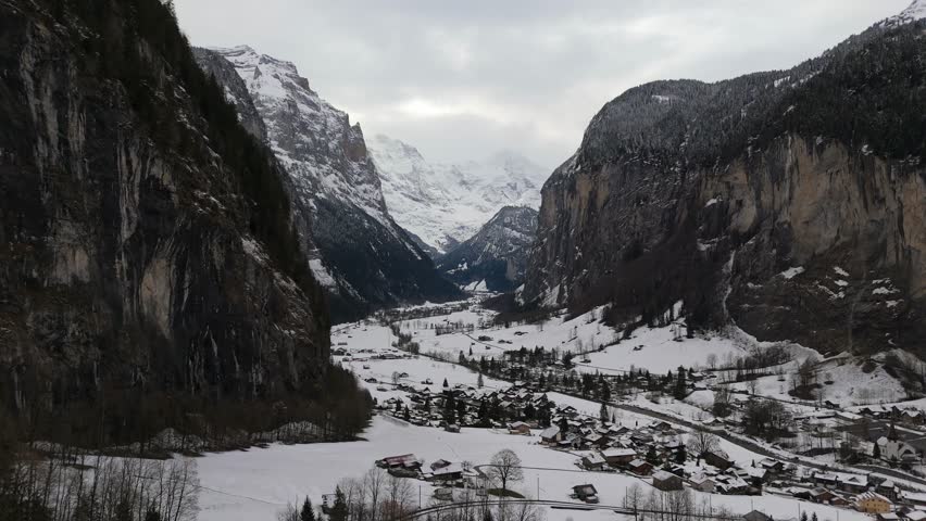 Lauterbrunnen Valley and Snowy Mountains on Cloudy Winter Day. Swiss Alps. Switzerland. Aerial View. Moving Forward, Tilt Up. Reveal Shot
