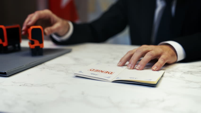 Canadian customs officer stamps denied in a passport, refusing traveler's entry