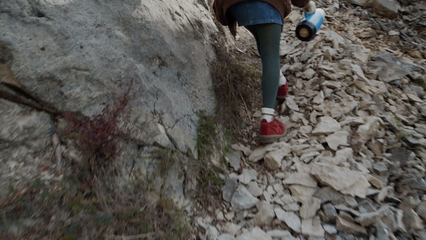 Anonymous Young Woman walks through the Rocky Trail in a Narrow Canyon with Steep Cliffs