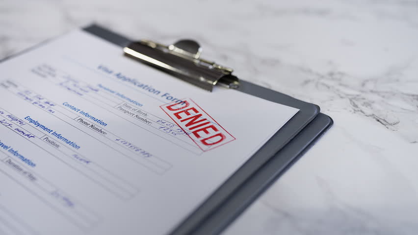 Visa application form gets rejected as a hand stamps a denied seal on document