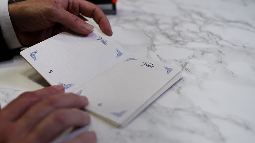 Customs officer stamps a denied seal in a UK passport, refusing person's entry