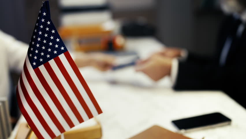U.S. official hands a passport to a woman, approving her visa application