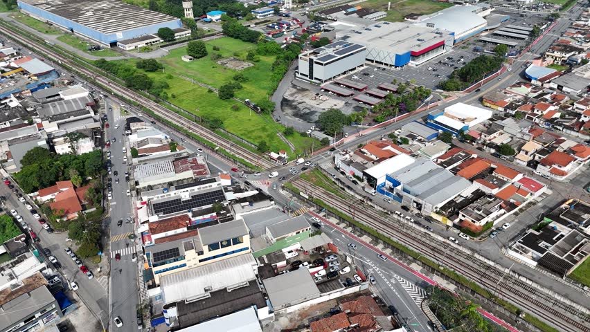 Aerial view of a busy intersection in Mogi das Cruzes, São Paulo, Brazil, where vehicles cross over train tracks, highlighting urban mobility, transportation, and city infrastructure