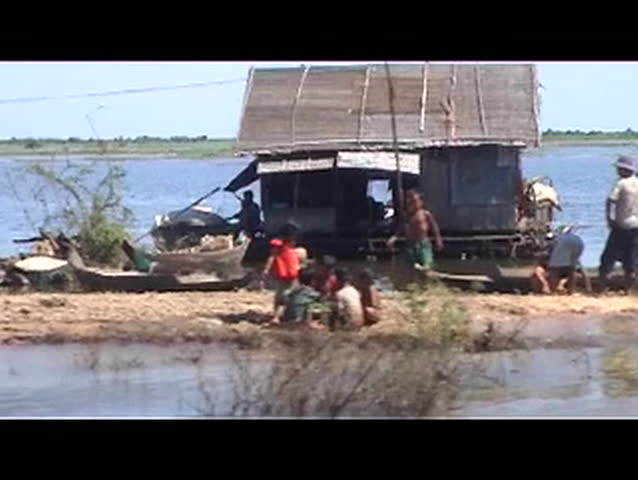 A man negotiating a sandbank through a floating village in the mekong delta on Tonle Sap Lake in Cambodia on a motorbike.
