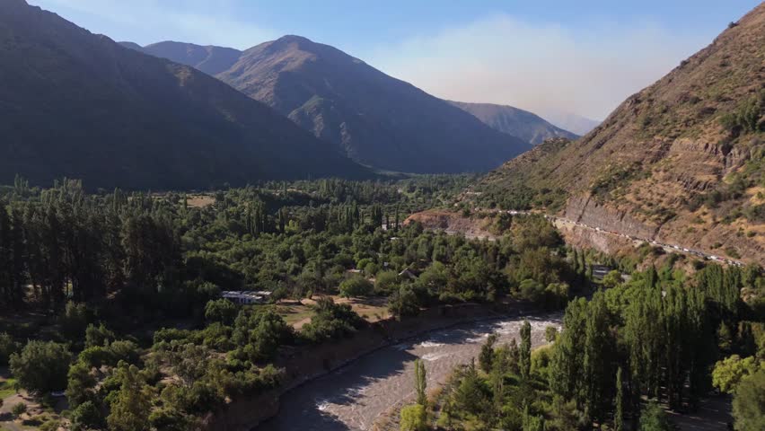 Maipo River on El Toyo Road surrounded by trees, with hills around it, Chile