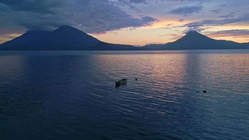 Birds flying across a calm lake during sunrise, Guatemala