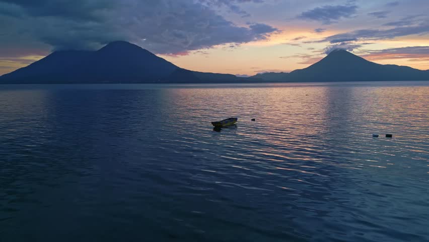 Birds flying across a calm lake during sunrise, Guatemala