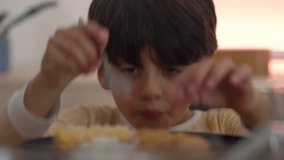 Young boy eating with a spoon, enthusiastic expression, close-up of meal interaction, enjoying homemade food, demonstrating dining etiquette and family mealtime - Powered by Shutterstock - Get 15% off with code: PIKWIZARD15