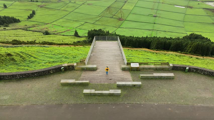 Drone tilt-up reveal of girl in yellow jacket exploring Serra do Cume viewpoint