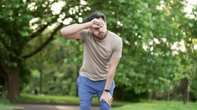 Adult runner has shortness of breath during a run in city park. Athlete feels tired. Sportsman rests his hands on his knees, taking a rest break, he's breathing heavily, wipes sweat from his forehead - Powered by Shutterstock - Get 15% off with code: PIKWIZARD15