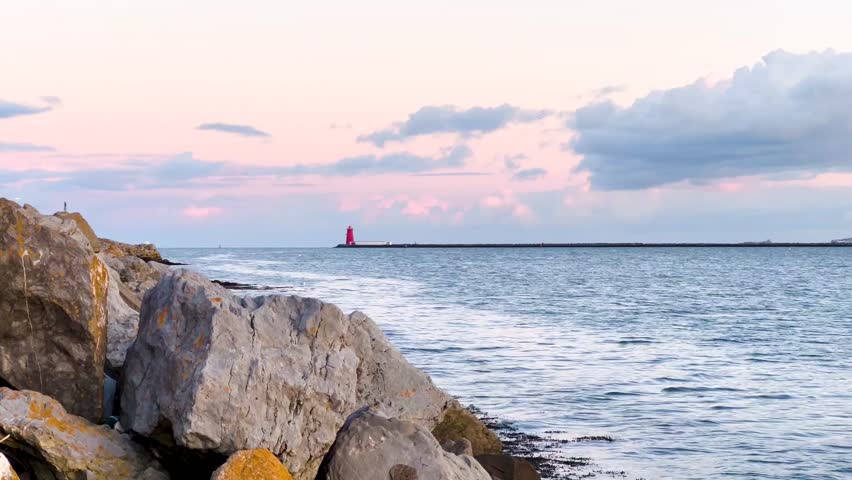Golden Hour at Poolbeg Lighthouse: Scenic Dublin Coastline with Calm Waves and Rocky Shoreline