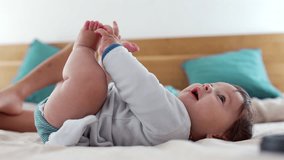 Baby laughing while lying on bed, playfully holding feet and enjoying a happy moment, capturing joy and natural expression in a relaxed family setting - Powered by Shutterstock - Get 15% off with code: PIKWIZARD15