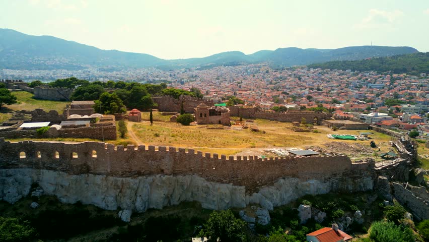 Drone shot going wider revealing the majestic Castle of Mytilene, Greece, on a bright sunny day.