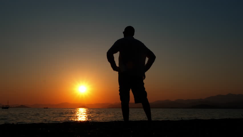 Tourist man silhouette against dusk ocean. A male traveler silhouette enjoy the dusk horizon during summer trip.