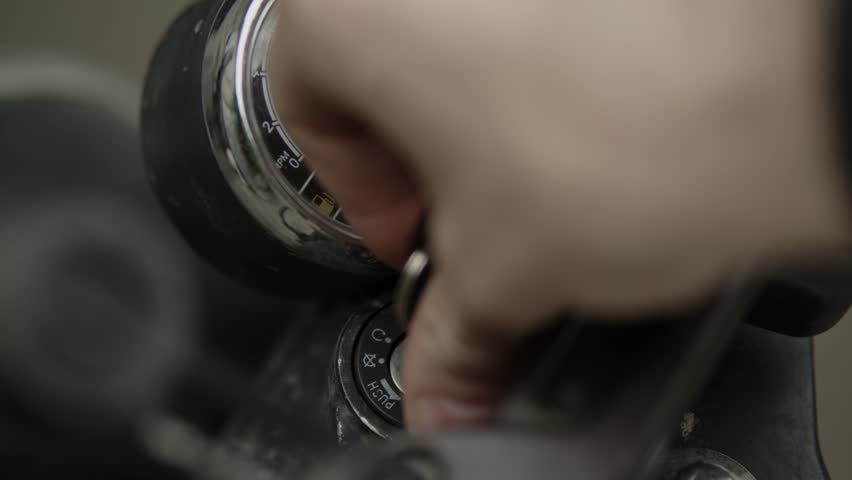a biker stands near a motorcycle, inserts the key into the ignition switch of the motorcycle and turns the key, turning on the ignition of the motorcycle, day