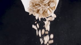 Oat flakes falling from open bag in slow motion on black background, representing healthy breakfast and morning routine - Powered by Shutterstock - Get 15% off with code: PIKWIZARD15