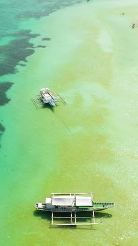 Boats floating over the turquoise sea water with sun reflection. Bantayan Island, Cebu. Philippines. Vertical view.