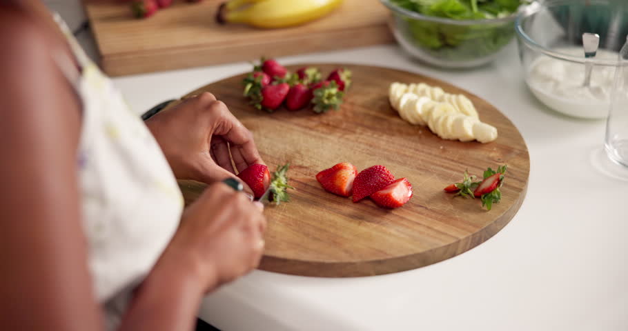 Person, detox and hands cutting fruits in morning breakfast for diet nutrition, wellness health or vitamins. Woman, strawberry and meal preparation for vegan shake, lunch or smoothie in house kitchen