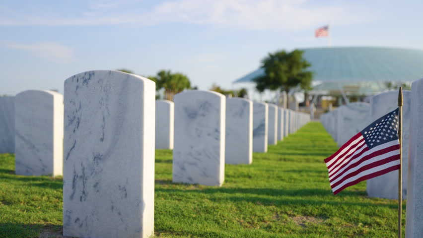 American army Sarasota National Cemetery with rows of white tombstones and USA flag on green grass. Memorial Day concept.