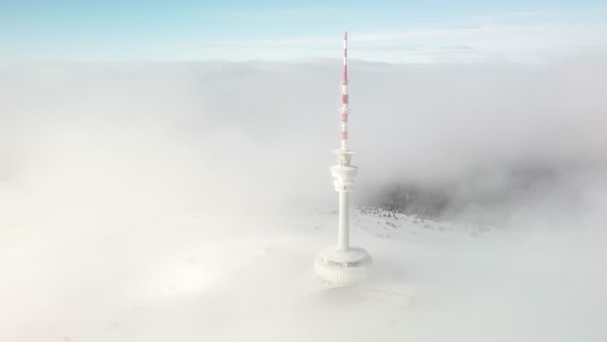 Transmission And Lookout Tower Shrouded By Fog And Clouds During Winter In The Peak Of Praded Mountain In Czech Republic. - aerial shot