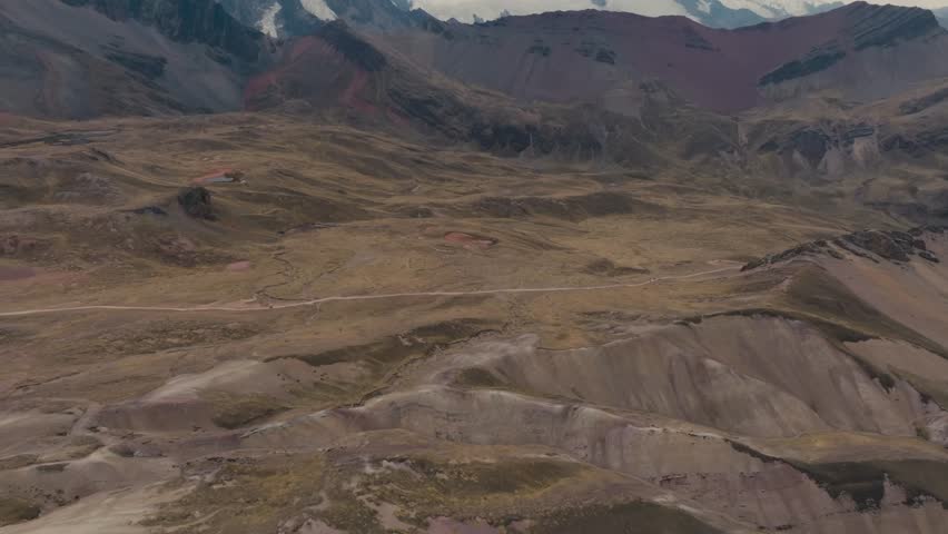 Rugged Terrain With Countryside Road Near Snow Mountains In Cusco Peru. Aerial Tilt-up Shot