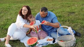 Dad, mom and girl enjoying picnic sitting on grass in park, enjoying tasty watermelon slices, treating each other, having fun, laughing. Summer snack in park. Happy family on summer picnic outdoors - Powered by Shutterstock - Get 15% off with code: PIKWIZARD15