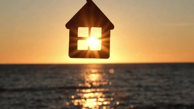 Silhouette of house shaped keychain on background of sea sunset in sun rays. Mortgage loan, real estate purchase, sale and rent. Sweet home and family. Solar energy concept - Powered by Shutterstock - Get 15% off with code: PIKWIZARD15