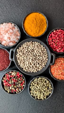 Variations of spices, allspice, turmeric, paprika, salt in ceramic bowls on a dark concrete background