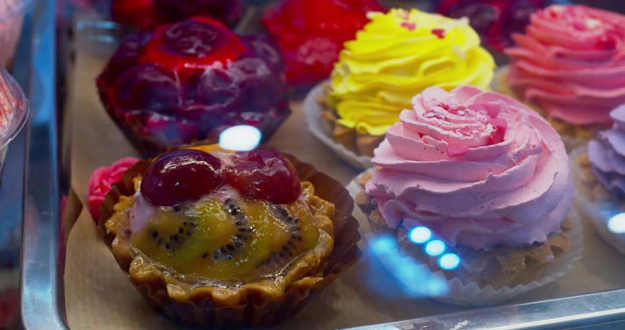 Sweet food. Many beautiful bright cakes are on display. Shoot of confectionery through the glass of the display case. Close-up.