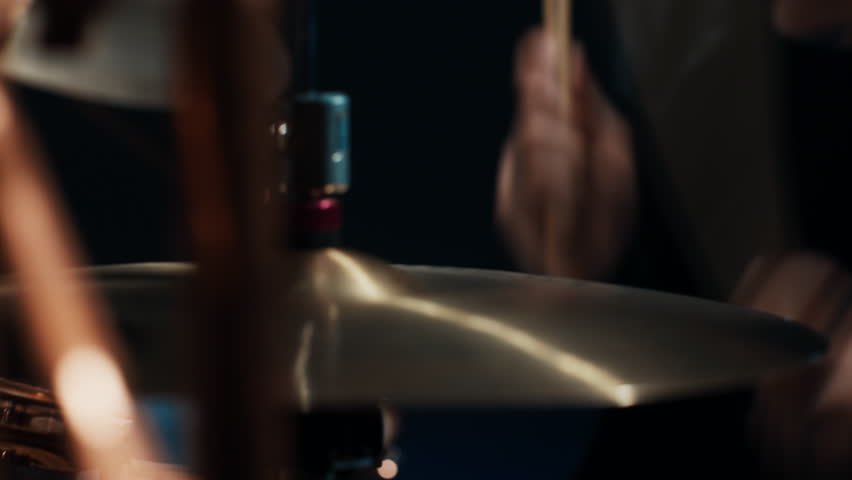 Closeup view of drumsticks in hands of professional drummer, creating drum beat . Musician punching drums and cymbals, rock star or jazz band performing on stage in music hall, modern style of music