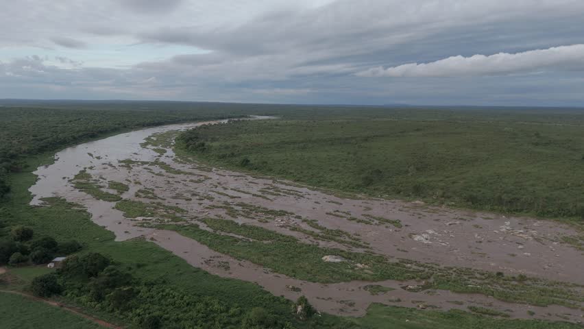 Cinematic aerial downward tilt of a flowing seasonal river that