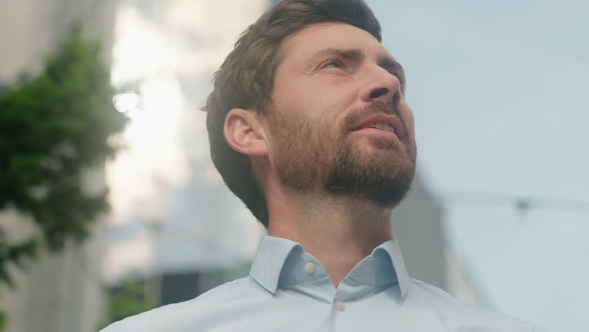 Close up smiling happy Caucasian middle aged adult man thinking looking around male guy business employer businessman manager inspired in city office building sun sky sunny insurance hope religion
