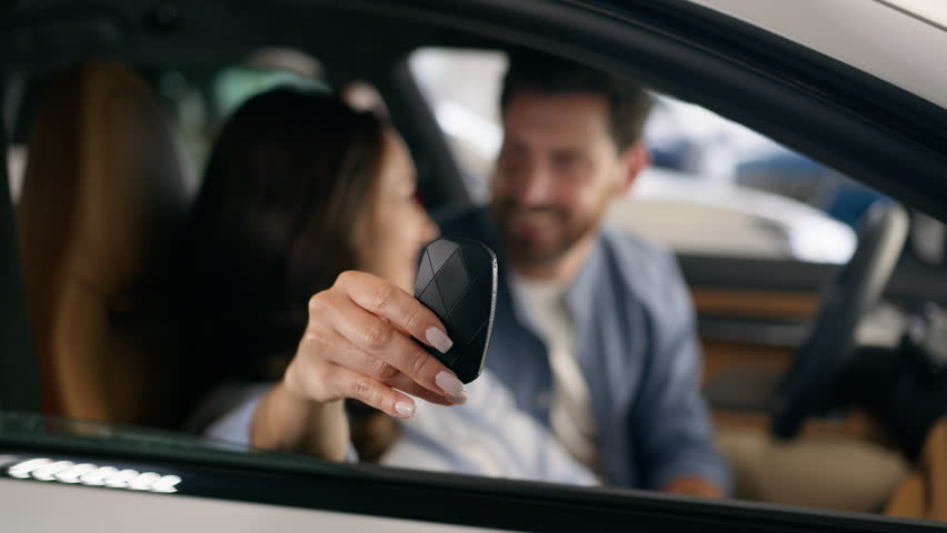 Caucasian couple man woman girl guy female male family hugging cuddling happy smiling looking at camera celebrate buying own vehicle transport holding key in new car buying auto inside automobile